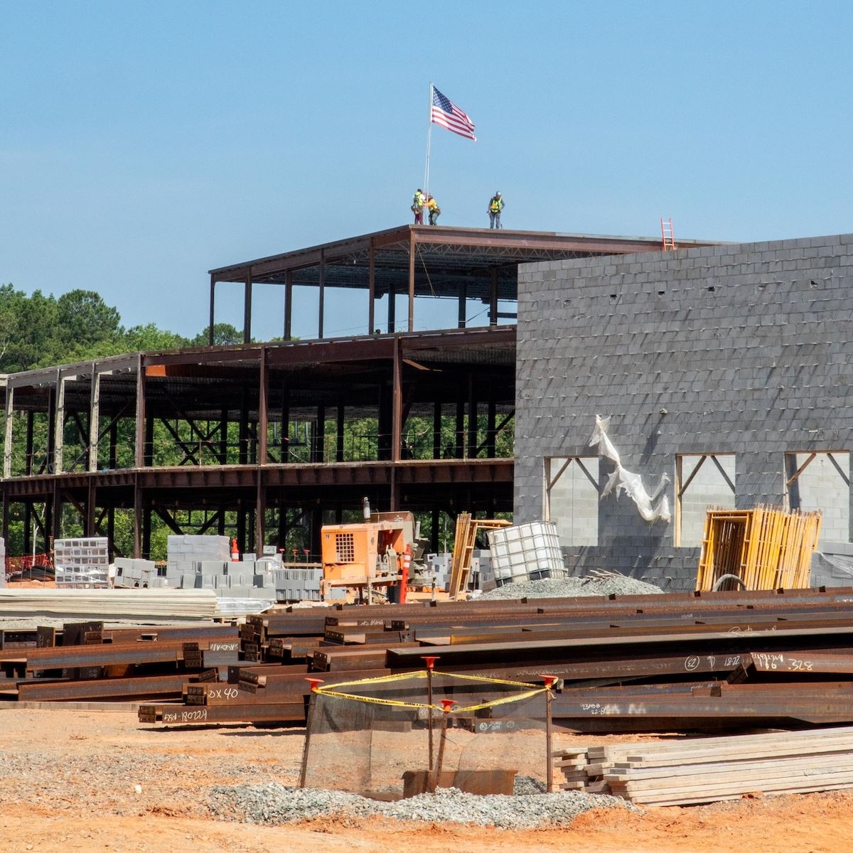  Construction crews raise a flag to mark the placement of the final beam at Felton Grove High School